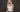 Frau mit langen, welligen platinblonden Echthaar Extensions vor dunklem Hintergrund.